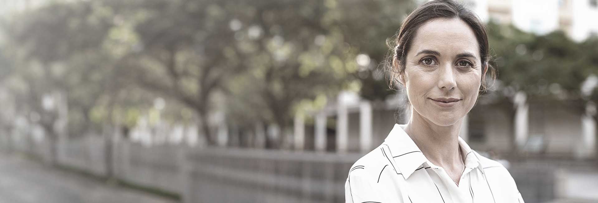 Woman standing outdoors, smiling confidently