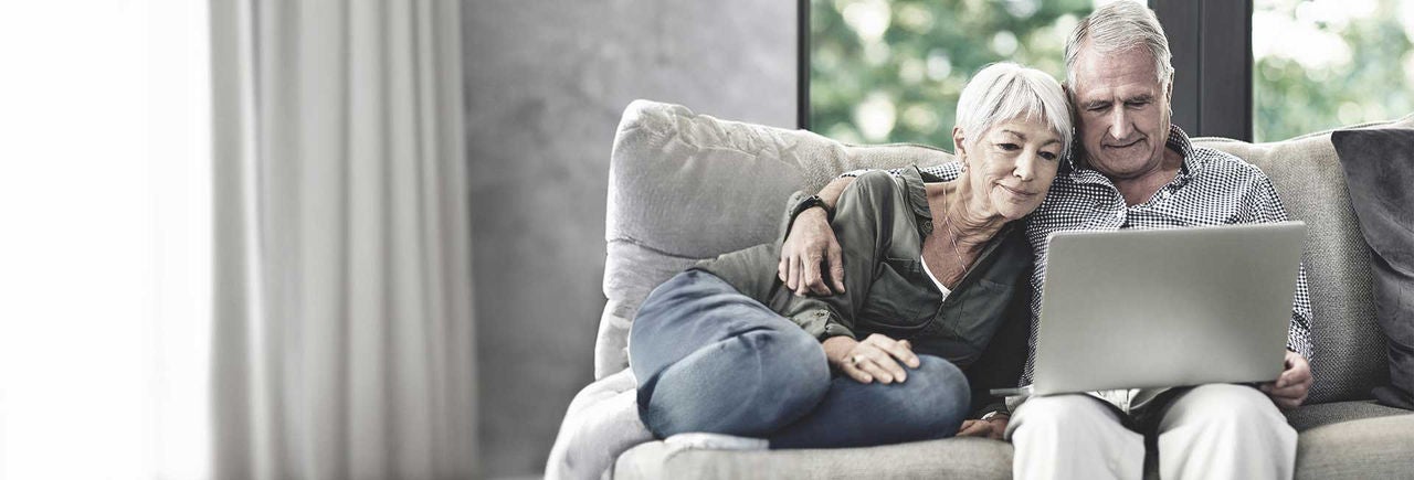 Senior couple at home searching for a pain centre on their computer