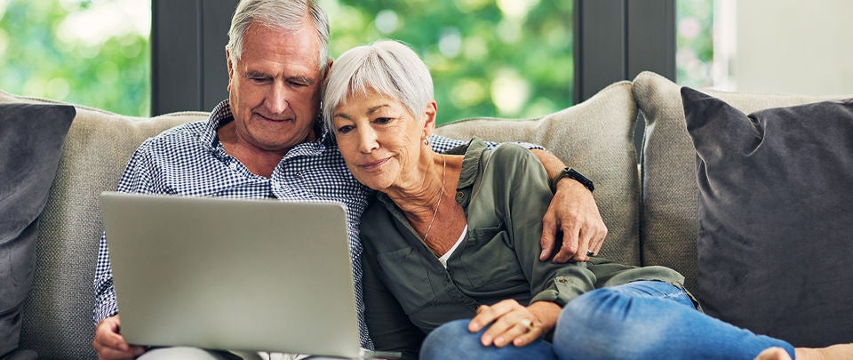 Senior couple at home searching for a pain centre on their computer