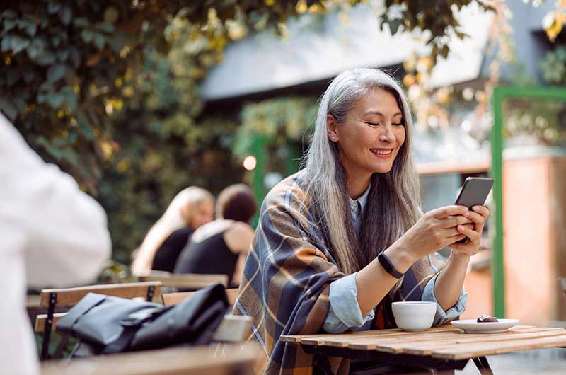   Woman smiling using smartphone at a café